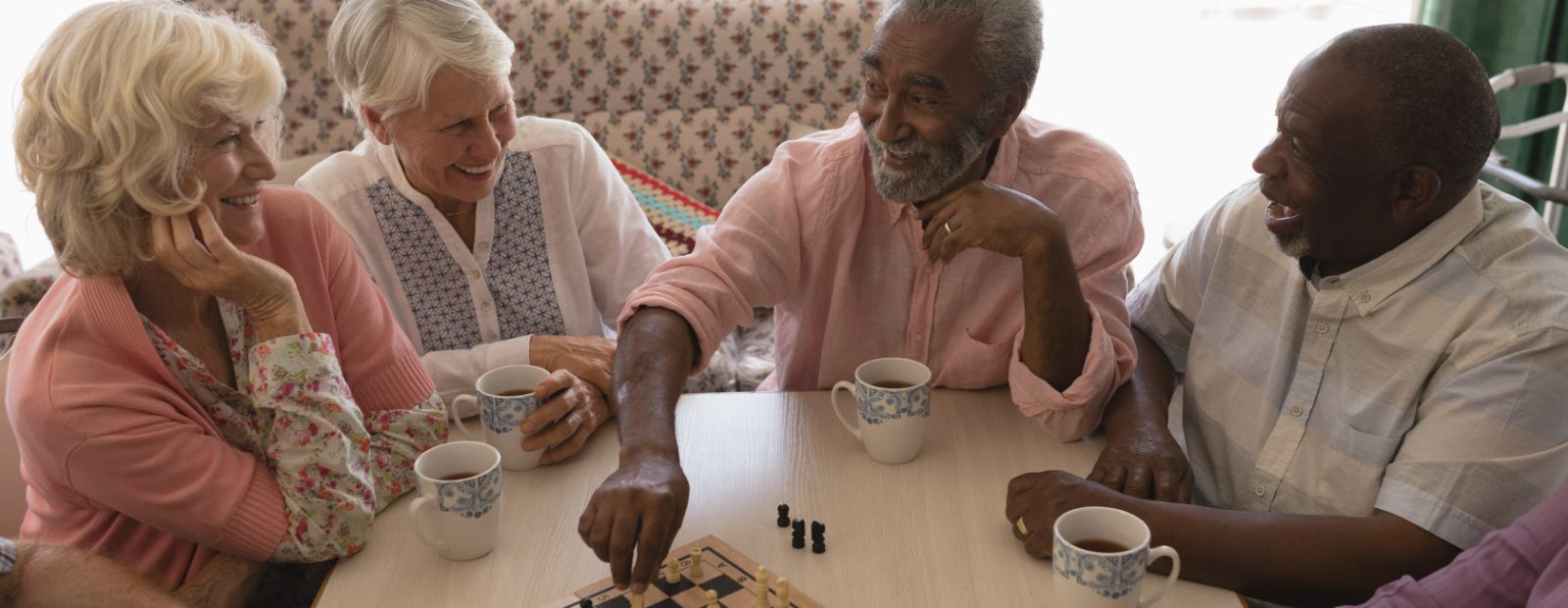 A diverse group of older adults talking and playing a game over coffee.