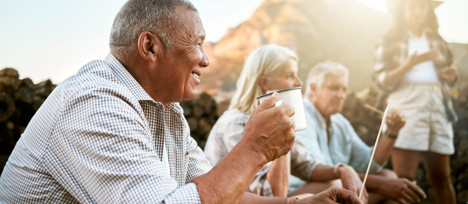 An older man enjoying coffee outdoors with friends.